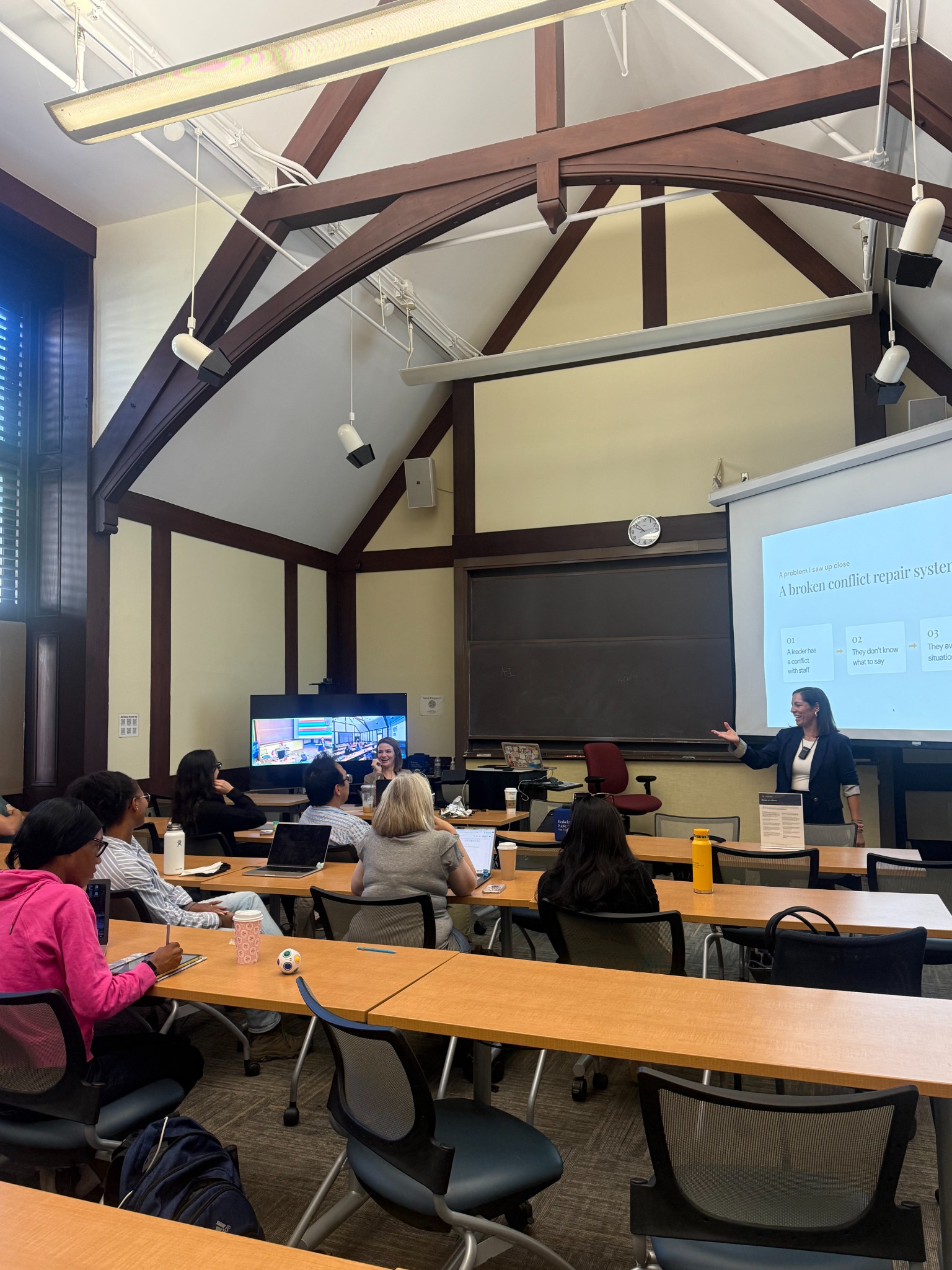 Dr. Isa teaching in a classroom with participants seated at tables.