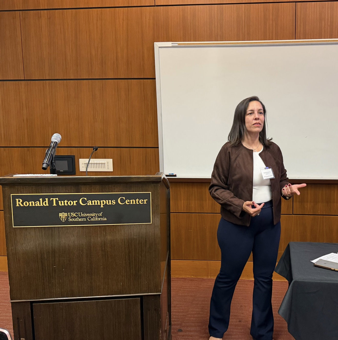 Dr. Isa teaching beside a podium and whiteboard at USC.